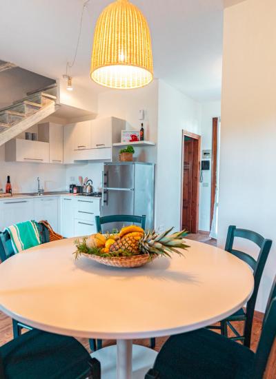 Modern kitchen with round table and wooden staircase.