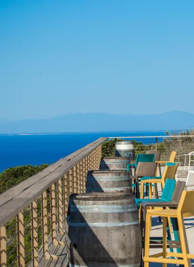 Panoramic terrace with sea view, colorful chairs, and closed umbrellas.