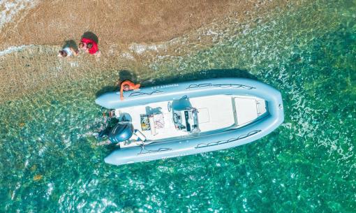 Gommone vicino alla riva con tre persone in acqua.