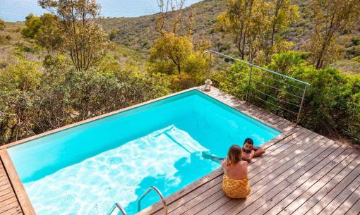 Pool mit Meerblick, umgeben von Natur.