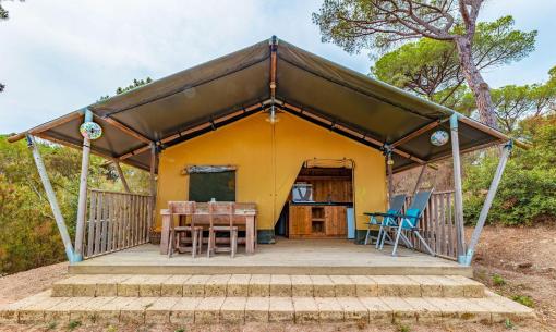 Tenda glamping con veranda in legno immersa nella natura.