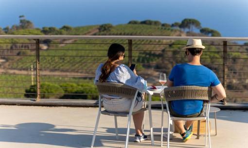 Coppia seduta su terrazza con vista mare e vigneti.