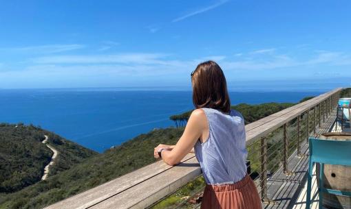 Donna guarda il mare da una terrazza soleggiata.