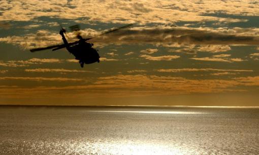 Elicottero in volo al tramonto sopra il mare scintillante.