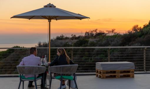 Couple seated at sunset on a terrace with an umbrella.