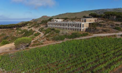 Stone building among hills and vineyards, sea view.