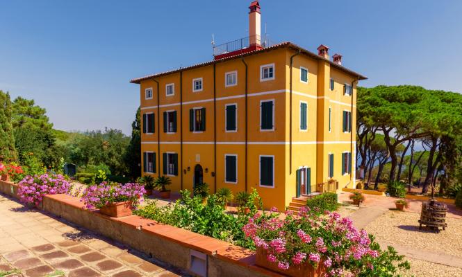 Villa colorata con giardino fiorito e vista sul mare.